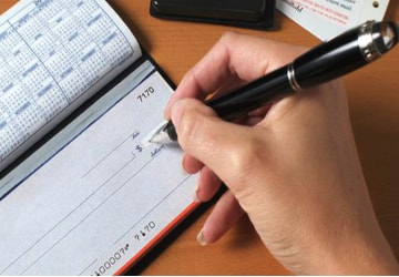 A person writing on a check with a pen.