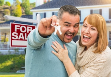 A man and woman holding keys to their new home.