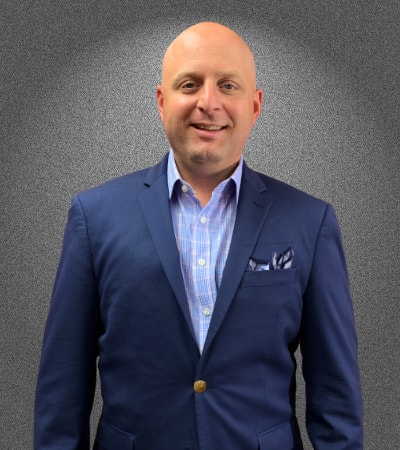 A man in a suit and tie standing next to a wall.